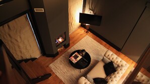 A modern living room with a fireplace, a sofa, a coffee table, and a lamp. - Suitehotel Posthoorn (Monnickendam)