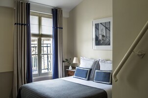 A hotel room with a bed, a nightstand, a lamp, and a window with curtains.