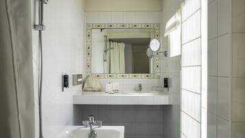Un baño con ducha, lavabo, espejo y bañera.