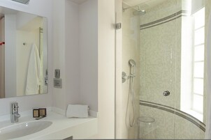 Un bagno moderno con uno specchio grande, un lavandino bianco e un box doccia in vetro.