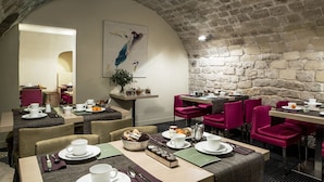 Un restaurante con techo de piedra y paredes de ladrillo, con mesas dispuestas, platos, vasos y cubiertos.