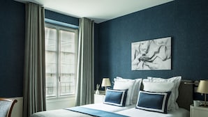 Un dormitorio con una cama grande, dos mesitas de noche, una ventana con cortinas y una obra de arte colgada en la pared.