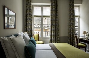 A hotel room with a bed, a chair, a desk, and a window with curtains. - Hôtel de la Place du Louvre (Paris)