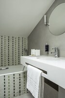 A modern bathroom with a white sink, a large mirror, and a towel rack.