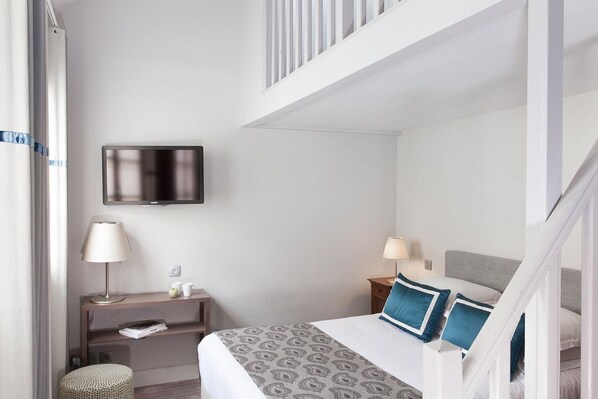 A hotel room with a bed, bedside tables, a TV, and a balcony. - Hôtel de la Place du Louvre (Paris)