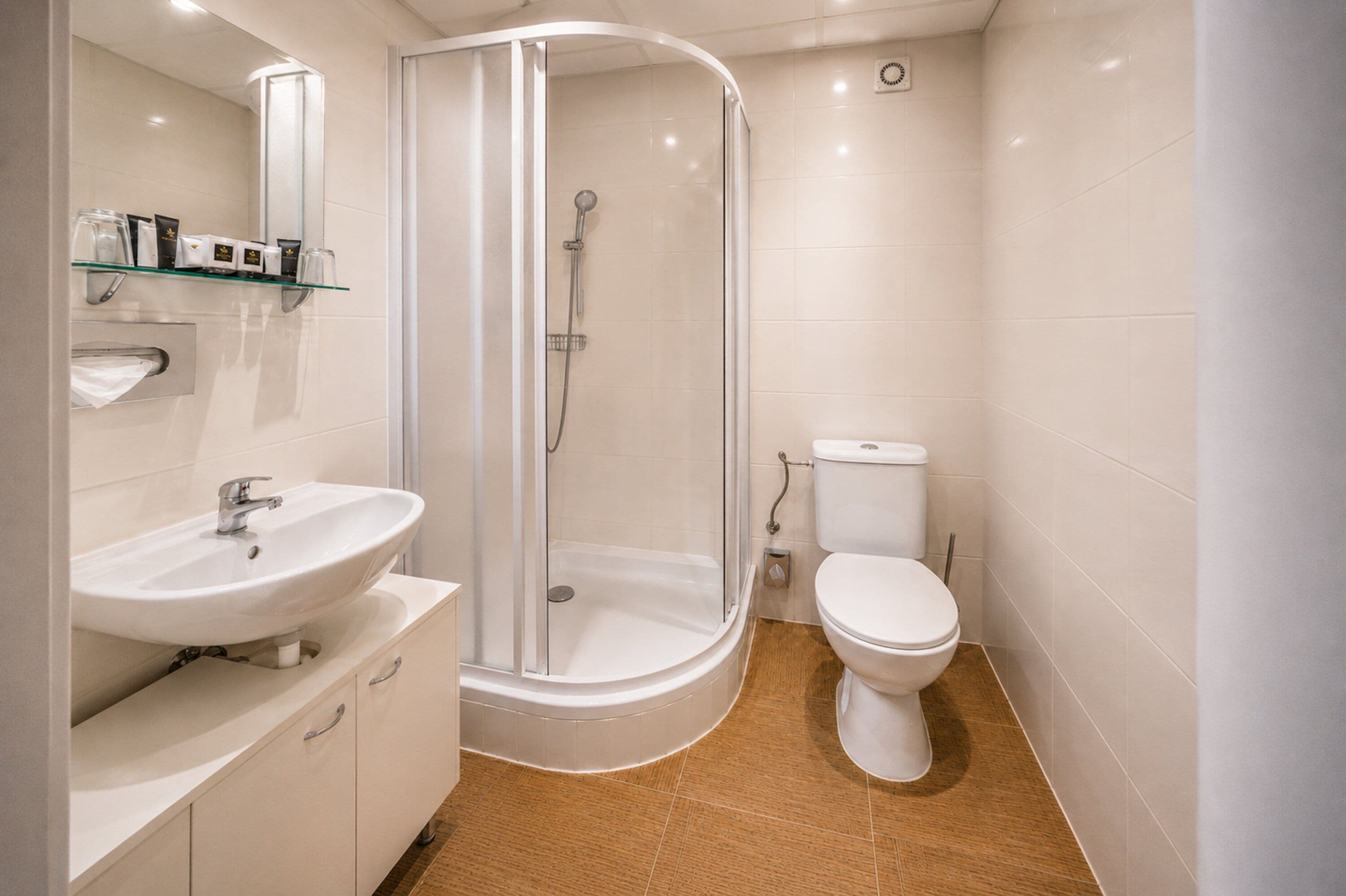 A modern bathroom with a glass-enclosed shower, a white sink, and a toilet.