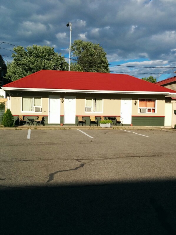 Un motel à deux étages, avec un toit rouge et des murs de couleur beige, et un parking situé à l’avant.