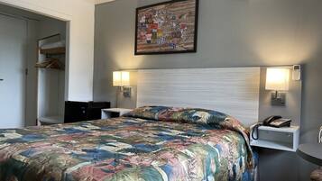 Habitación de hotel con una cama grande, un escritorio, una silla, un armario y un cuadro en la pared.
