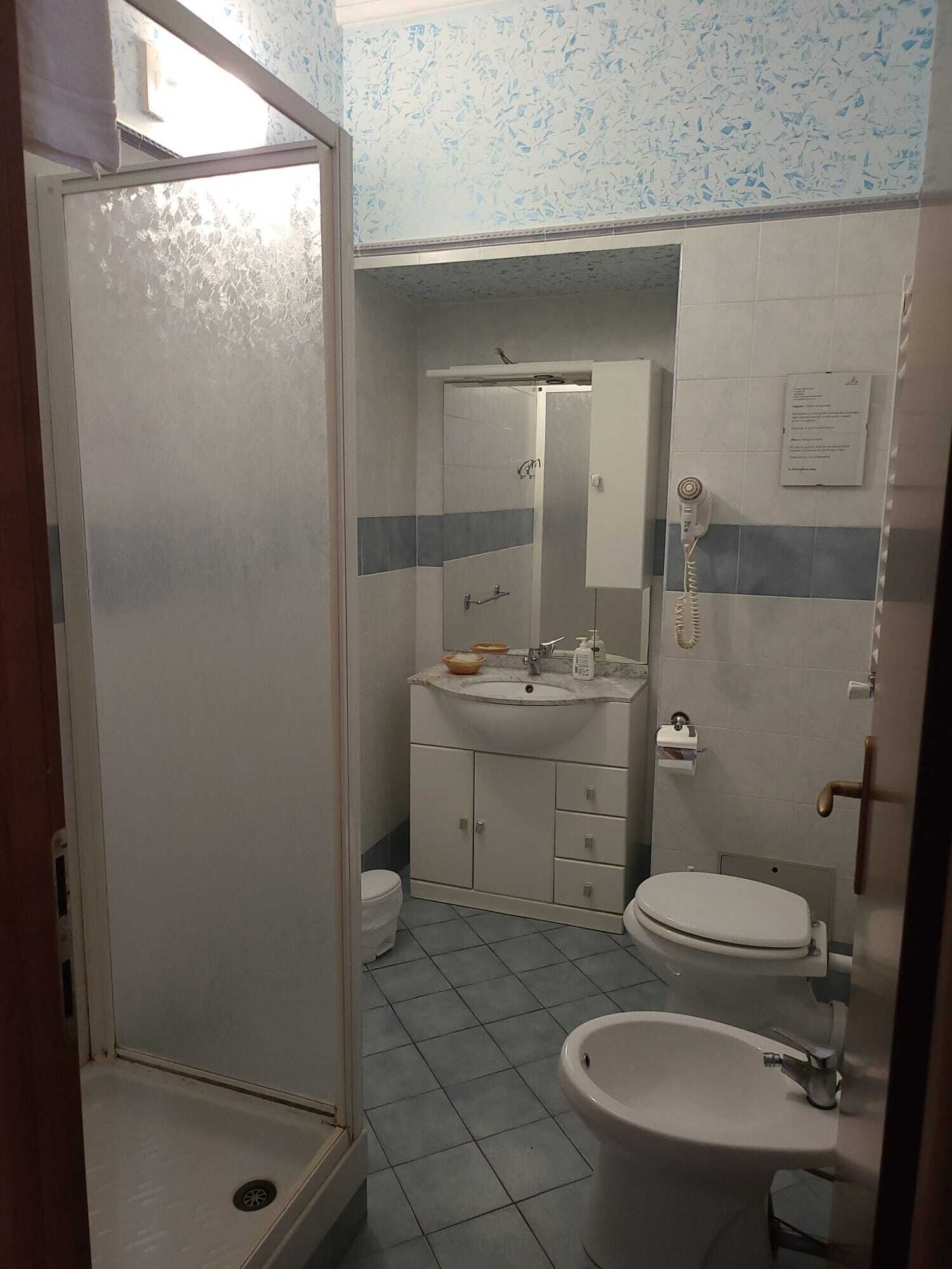 Un baño con ducha, inodoro y dos lavamanos.