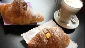 Dos cruasanes sobre una mesa con una taza de café.