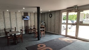 A hotel lobby with a stone wall, a television mounted on the wall, and a reception desk. - Glisy Hotel (Glisy)