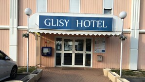 The exterior of Glisy Hotel with a brick entrance, a reception area, and a parking space. - Glisy Hotel (Glisy)