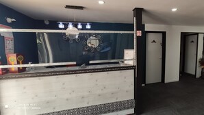 A reception area with a counter, a mirror, and a door with a sign. - Glisy Hotel (Glisy)