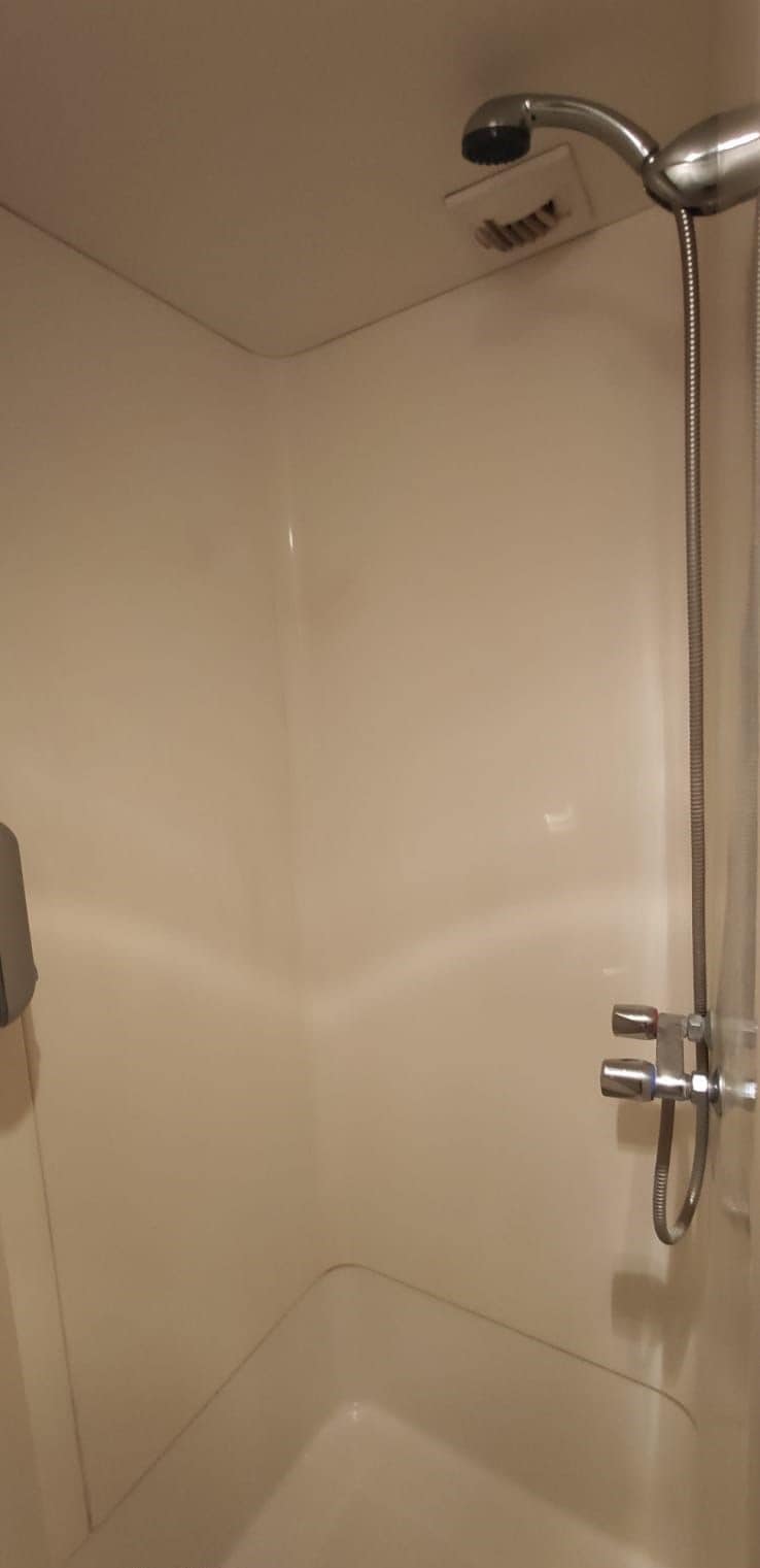 Un coin d’une salle de bain avec un pommeau de douche et un flexible de douche.