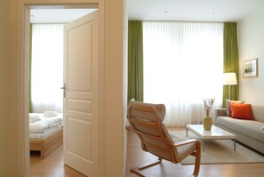 A hotel room with a bed, a chair, a sofa, a coffee table, and a lamp. - Aparthotel am Zwinger (Dresden)