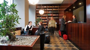 A lobby with a reception desk, seating area, and a large bookshelf. - Aparthotel am Zwinger (Dresden)