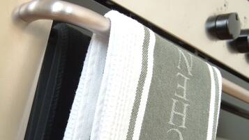 A towel hanging on a metal rack with a handle, a control panel with knobs and a red indicator light, and a white and gray striped towel.