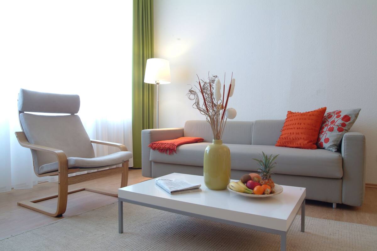 A modern living room with a sofa, a chair, a coffee table, and a lamp.