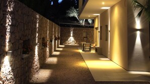 A modern building with a stone wall on one side and a flat roof on the other, featuring a well-lit interior and a clear sky. - Hotel Seventeen (Valbonne)