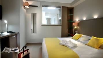 A hotel room with a bed, bedside table, lamp, and a mirror.