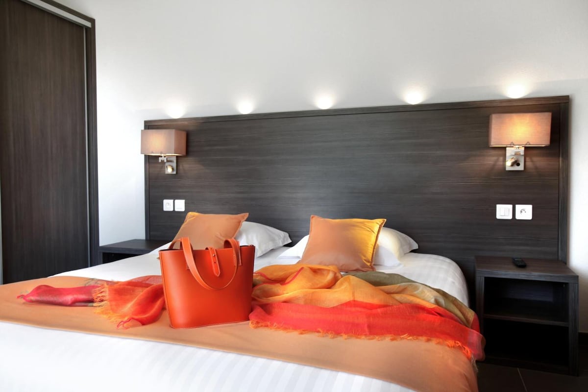 Een hotelkamer met een groot bed, twee nachtkastjes en een kledingkast.