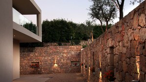 A modern outdoor area with a stone wall, a glass balcony, and potted plants. - Hotel Seventeen (Valbonne)