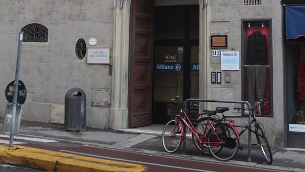 A hotel with a sign reading "HOTEL" above the entrance, a bicycle parked outside, and a storefront with a mannequin in the window. - Hotel Genzianella (Florence)