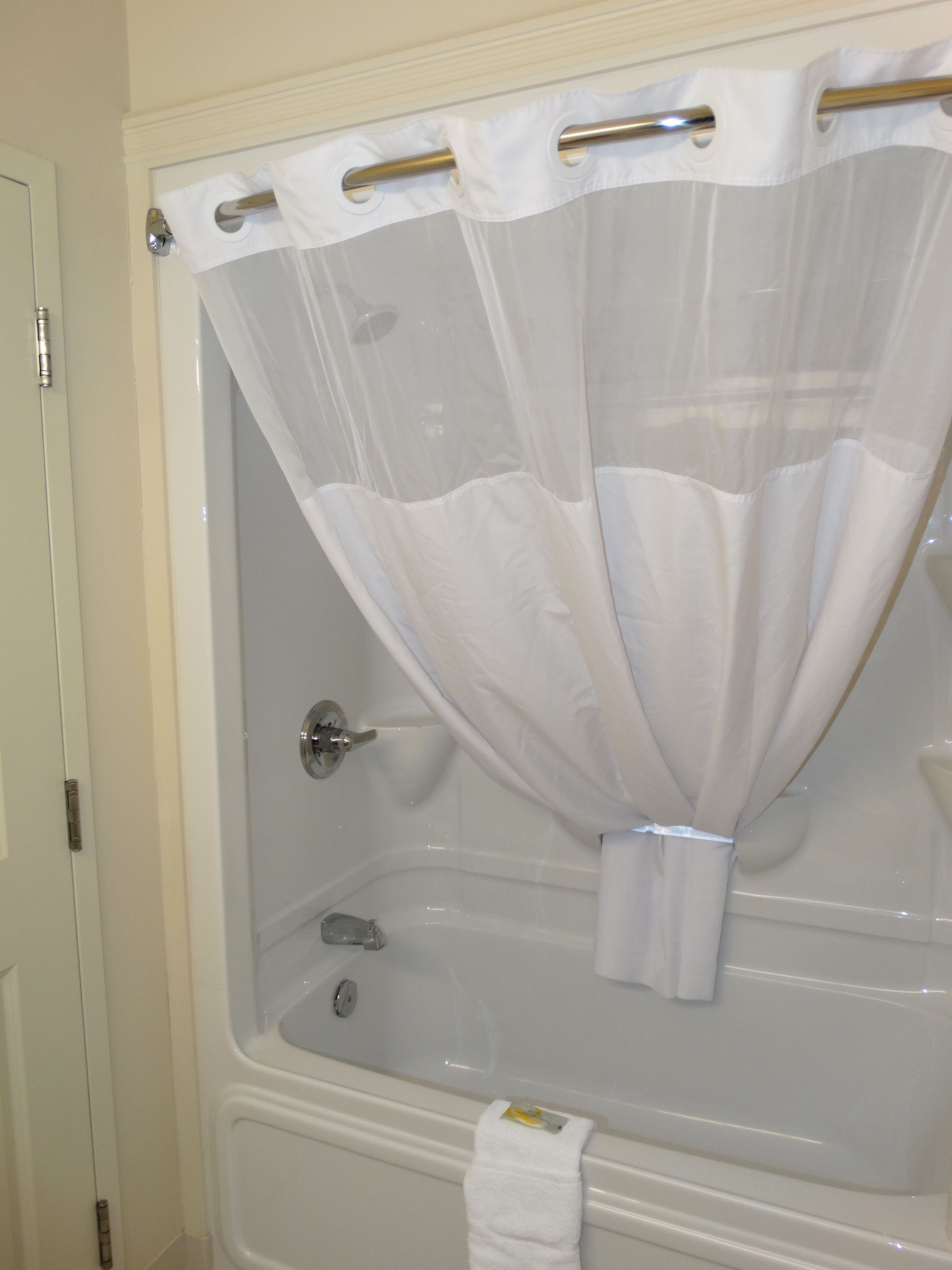 Ein Badezimmer mit einer Badewanne, einer Duschvorhang und einem Handtuch an der Wand.