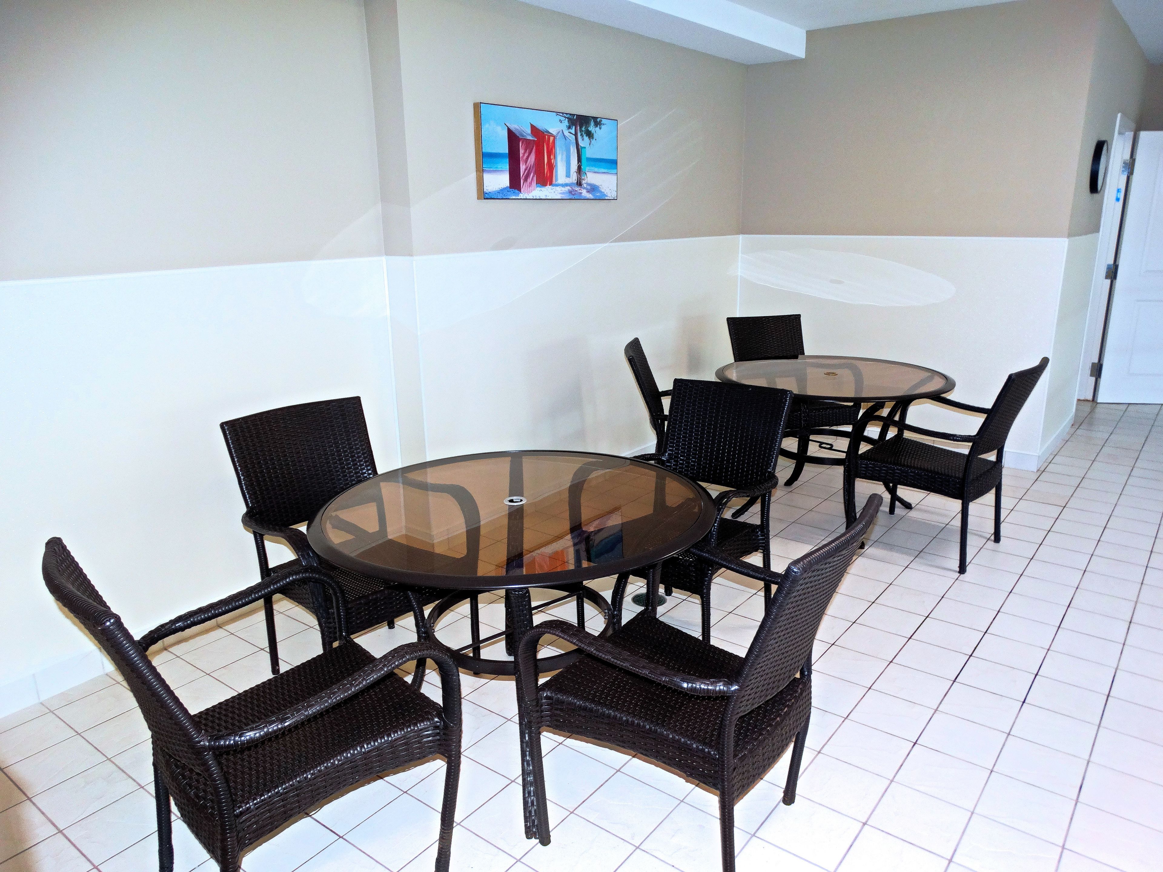 Un comedor con dos mesas redondas de vidrio y sillas de mimbre.