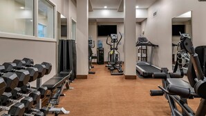 A gym with exercise equipment, a treadmill, and a bench. - Quality Inn & Suites Quispamsis (Quispamsis)