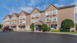 A multi-story hotel with a central entrance, multiple windows, and a parking lot. - Quality Inn & Suites Quispamsis (Quispamsis)