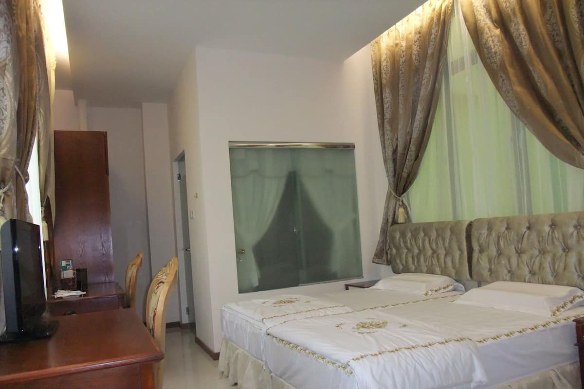 Quarto de hotel com uma cama, uma escrivaninha e uma televisão.