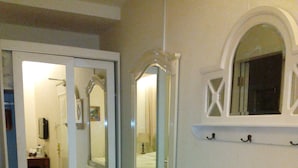 Un baño con un tocador blanco, un espejo grande y una pequeña ventana sobre el espejo.