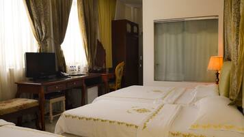 A hotel room with a bed, a desk with a television, a chair, and a wardrobe.