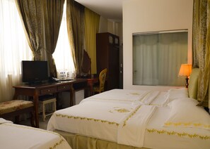 Una habitación de hotel con una cama, un escritorio con televisor, una silla y un armario.