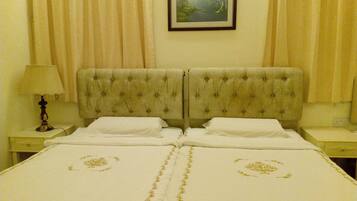 A double bed with a tufted headboard, two bedside tables, a lamp, and a framed painting on the wall.