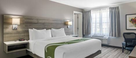 Una habitación de hotel con una cama grande, mesitas de noche, un escritorio y una silla.
