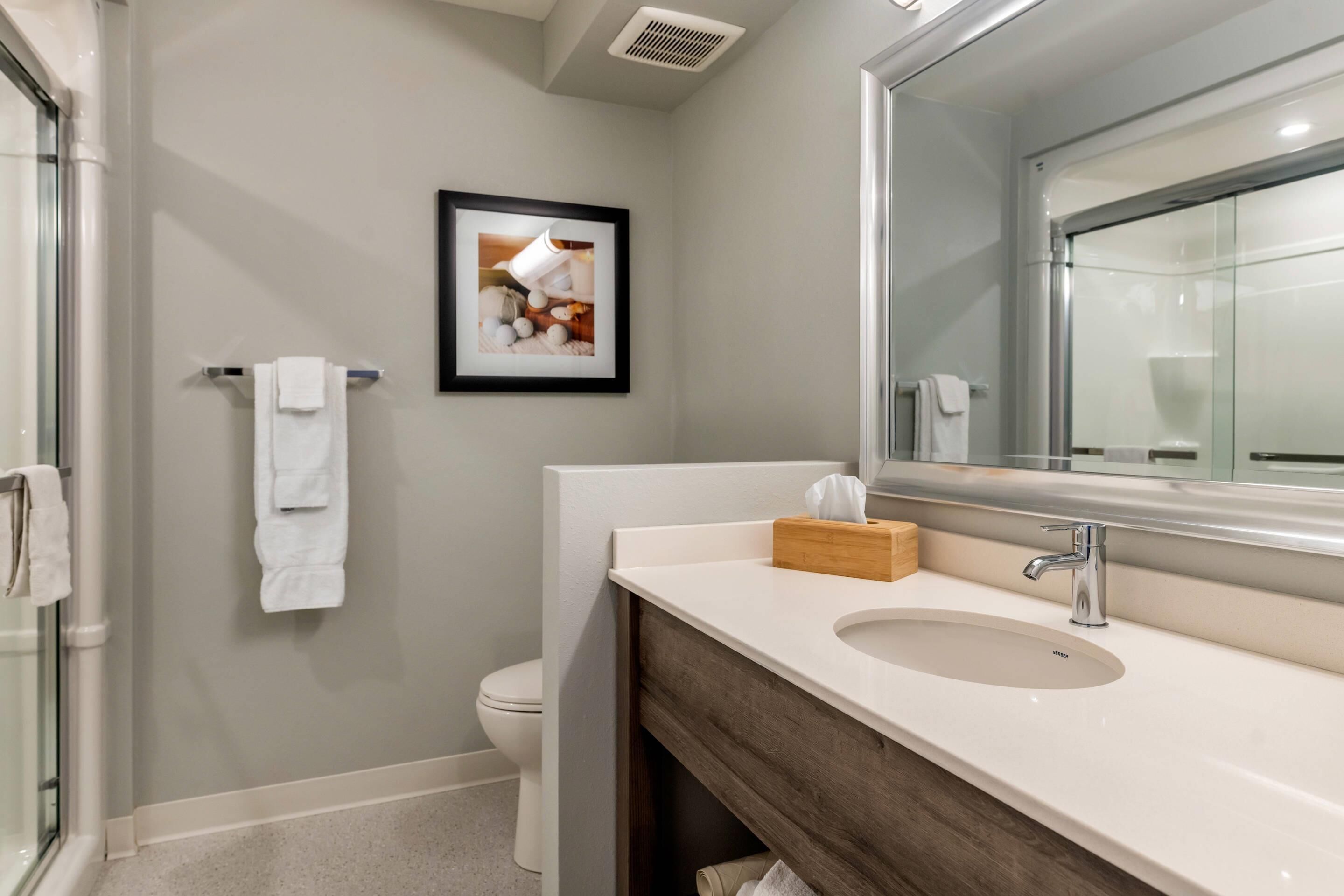 A modern bathroom with a large mirror, a sink, and a toilet.