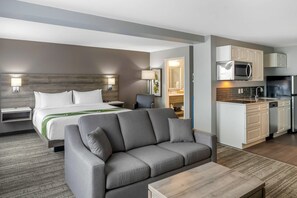 Une chambre d’hôtel moderne équipée d’un canapé, d’un lit, d’un bureau et d’une kitchenette.