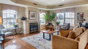 A spacious living room with a fireplace, comfortable seating, and large windows.