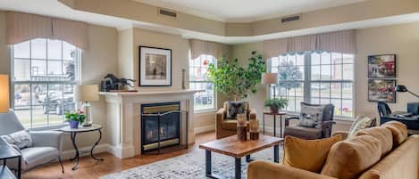 A spacious living room with a fireplace, comfortable seating, and large windows.