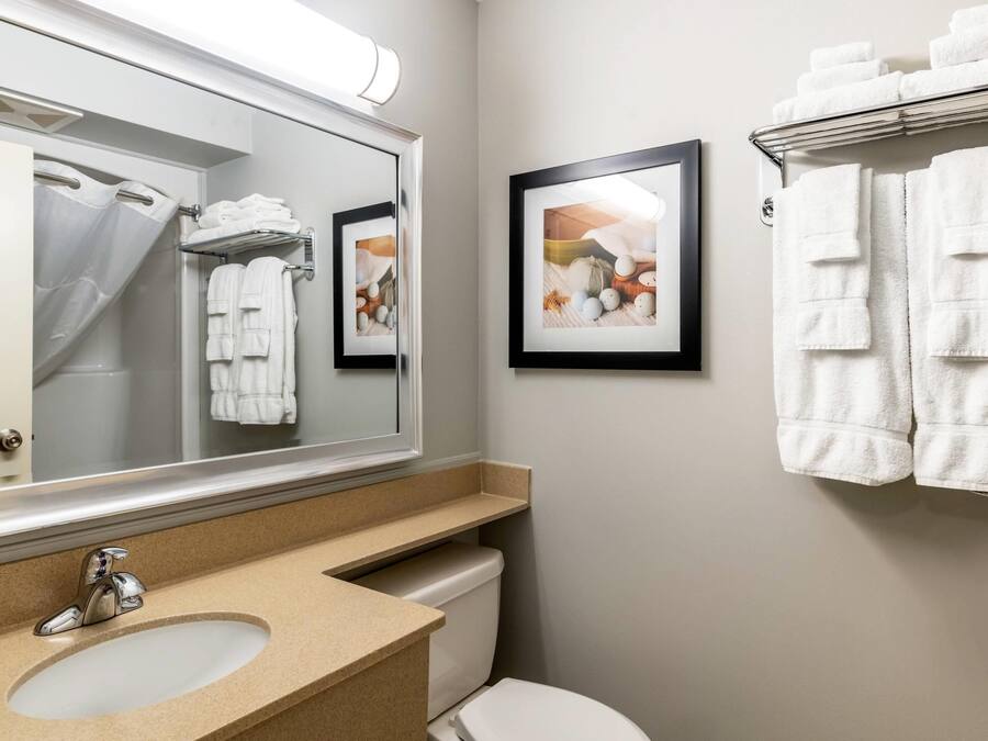 A bathroom with a sink, mirror, towel rack, and framed pictures on the wall.