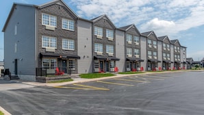 A row of multi-story buildings with a row of red chairs outside each entrance.