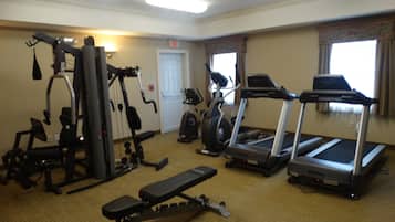A gym with various exercise equipment including a treadmill, elliptical, and weight machines.