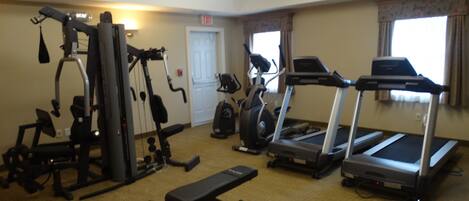 A gym with various exercise equipment including a treadmill, elliptical, and weight machines.