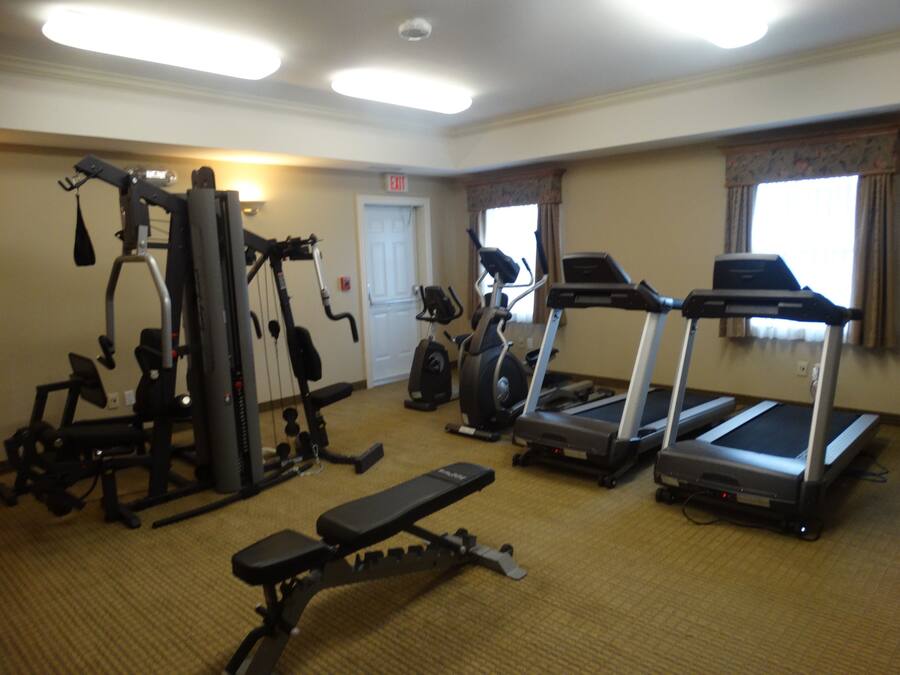 A gym with various exercise equipment including a treadmill, elliptical, and weight machines.