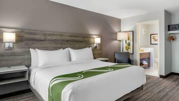 A hotel room with a large bed, two bedside tables, a chair, a desk, and a TV.