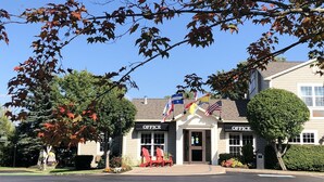 A building labeled "OFFICE" with a parking lot in front, surrounded by trees with autumn leaves.