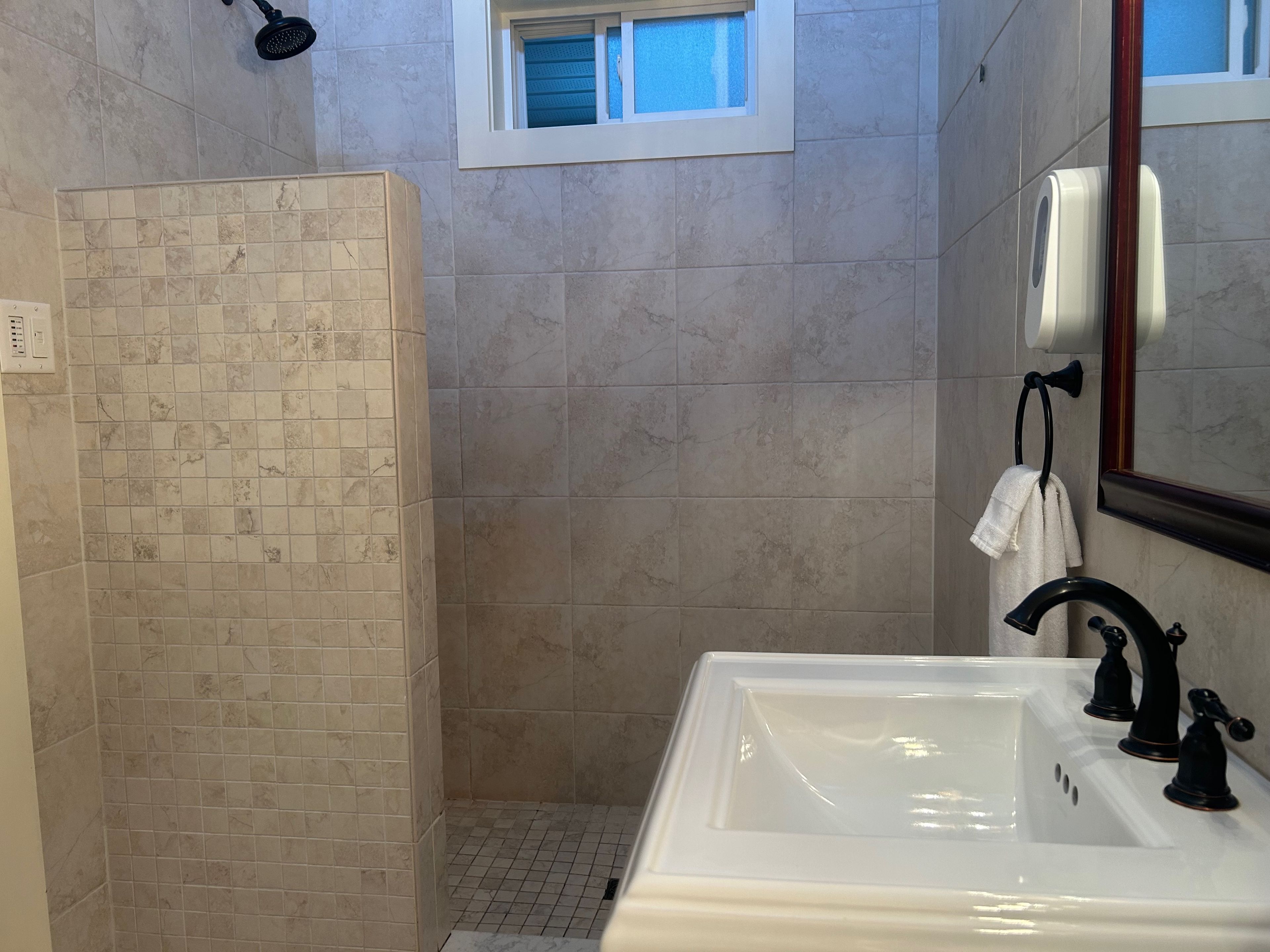 A bathroom with a shower, a sink, and a window.