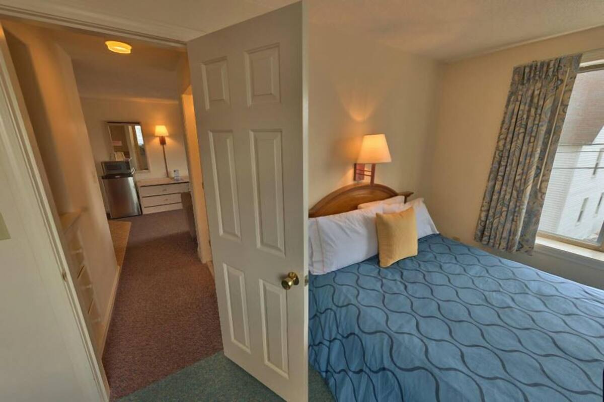 A hotel room with a bed, a desk, and a mirror.